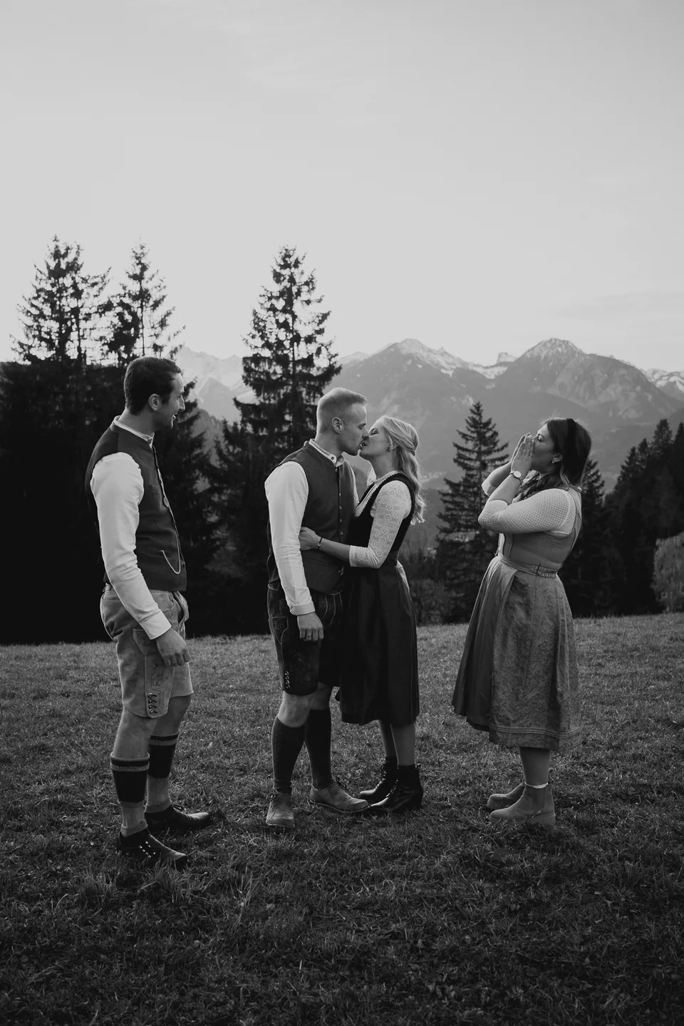 Brautpaar mit Gästen auf einer Almwiese, Schwarzweißaufnahme