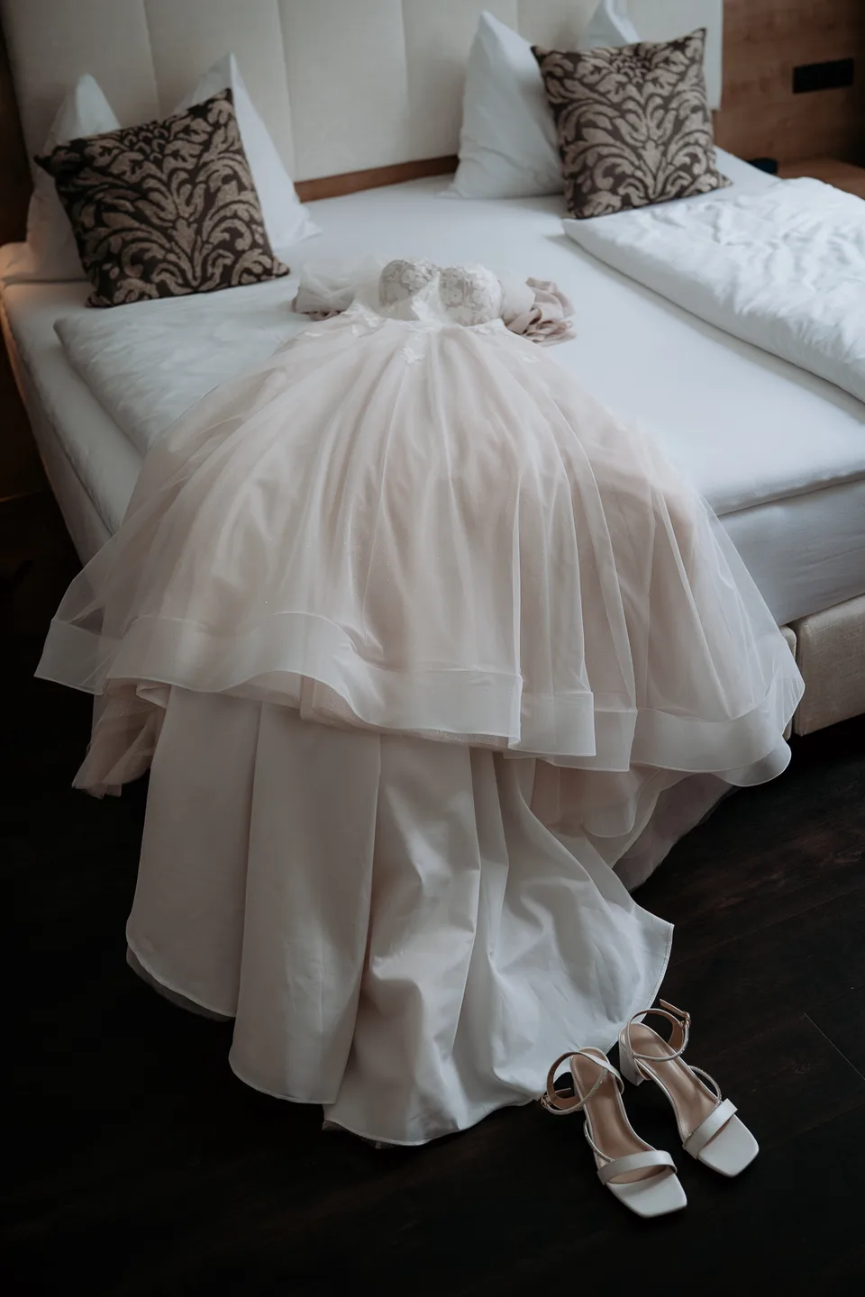 Brautkleid und Brautschuhe liegen bereit auf einem hellen Hotelbett